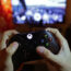 A teenager holding a controller to play the video game Forza Motorsport 5 on a Microsoft Xbox One console