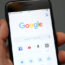 A person holds an iPhone showing the app for Google chrome search engine