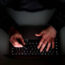 A laptop user with their hood up holding a bank card