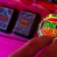A man's hand about to press the start gamble button on a fruit machine