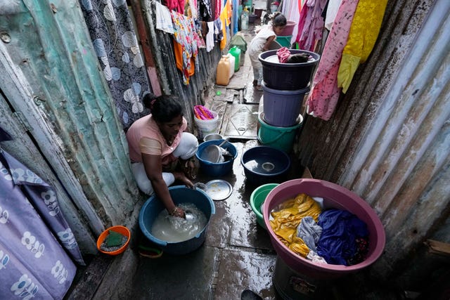 A woman washes utensils outside her house in Mumbai, India
