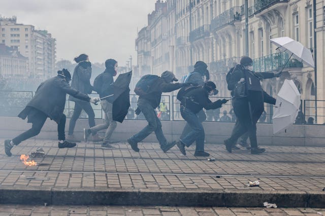 df9c502b85f04087a8b2a2feb1763f2c-1 Protesters shield with umbrellas as they scuffle with riot police during a rally in Nantes
