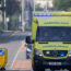 An ambulance with flashing blue lights driving along the road