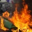 Demonstrators walk past burning rubbish bins during a demonstration in Paris