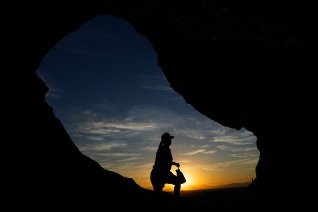 A hiker walks past the Hole-in-the-Rock at Papago Park during sunrise in Phoenix