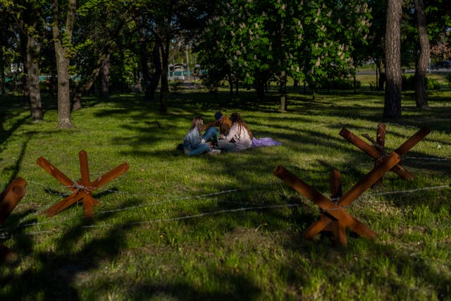 32aebf6cf8d647b3a40fc27d44ee345f People sit in a park next to anti-tank hedgehogs in Kyiv