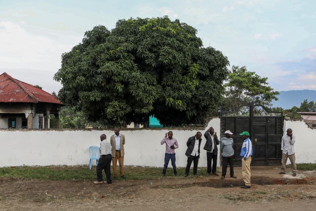 Plainclothes security forces and civilians stand outside the entrance to the school