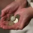 An elderly woman holding pound coins