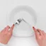 Hands holding cutlery over an empty plate