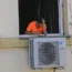 A worker takes a break by a newly installed air conditioner unit outside an apartment in Madrid