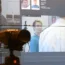 A facial recognition camera in front of a big screen