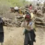 Women walk out of the forest carrying wood to use for cooking in Tsavo East, Kenya