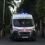 An ambulance leaves the courthouse past members of the media