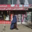 A woman walks past a beauty salon and dress shop in Kabul