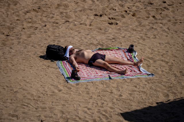 5c281bd973e14c71af5c122db580d308 A man sunbathes on the beach in Barcelona