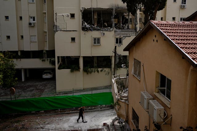 669889cd3c2540a7b66f3e4513f8b076 A municipality worker cleans the rubble from outside a damaged house a day after it was hit by a rocket fired from the Gaza Strip, in Rehovot, Israel