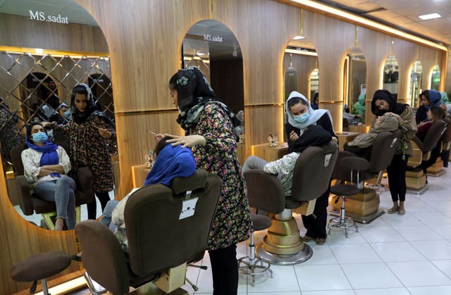 Beauticians put makeup on customers at a beauty salon in Kabul