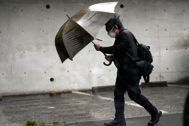 9c3b0725dd5d430494315c14b4a7b5d5 A person holds an umbrella against strong wind and rain on a street in Tokyo
