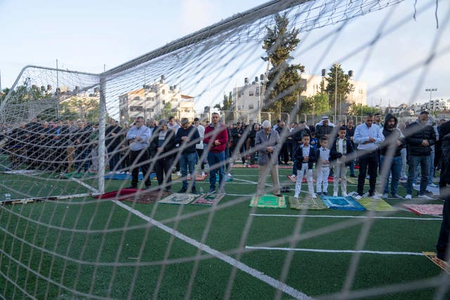 9f25d71c06704f7c937ed52c24e62834 Palestinian Muslims perform Eid prayers at a football pitch in the West Bank city of Beitunia