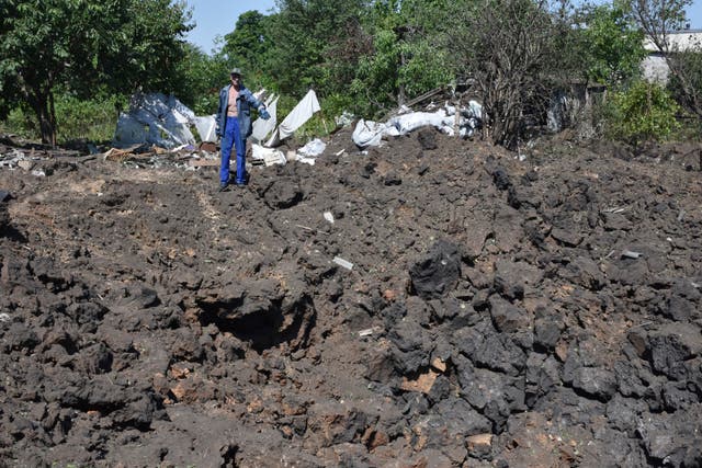 b6876fd3adfc4340bcf800cde319c35a A man gestures next to crater of an explosion by Russian shelling in a residential area in Kushuhum, near Zaporizhia, Ukraine
