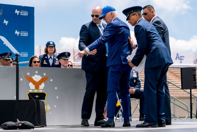 e47adae5aa9d4707a48791d90a7df3fb President Joe Biden points to sandbags after falling on stage during the 2023 United States Air Force Academy Graduation Ceremony at Falcon Stadium, at the United States Air Force Academy in Colorado Springs, Colorado
