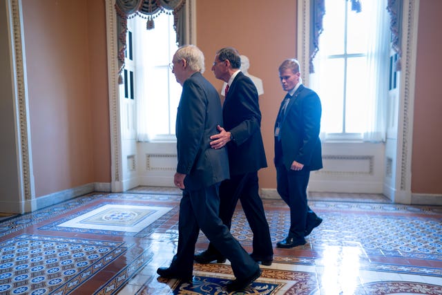 06eaeae725634b7da8adc2abfc60d253 Mitch McConnell, left, is assisted by John Barrasso, second from right, and a Capitol police officer