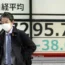 People walk in front of an electronic stock board showing Japan’s Nikkei 225 index at a securities firm Monday, March 20, 2023, in Tokyo