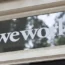 Signage outside the co-working office space group, WeWork, at Soho Square in London