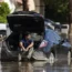 A man sits in his car as he waits for a tow after it got stuck in the mud