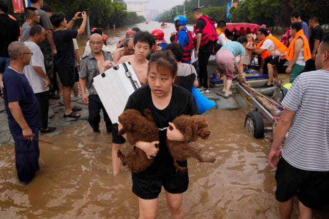 A woman carries her pet dogs as residents are evacuated in Zhuozhou in northern China’s Hebei province