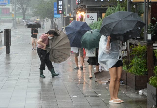 905cb875e13c4063ac587513f8601967 People struggle to hold onto their umbrellas in the rain and wind in Busan