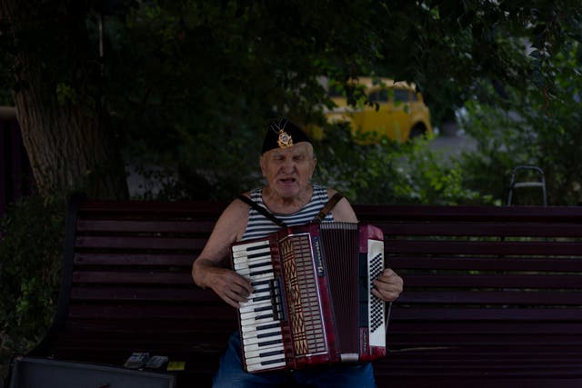 f4f6cd71b1b44536a3bf7fcbcf1fd74c A street performer sings while playing the accordion at a popular beachside attraction in Odesa