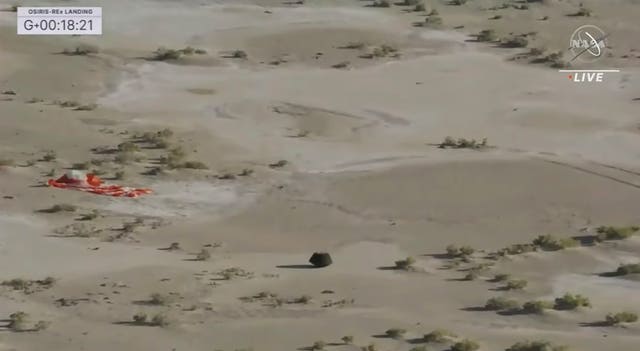 2df60c6fd2844f469b4640f2747be2e8 The capsule lying on the surface of the desert near the parachute after landing back on Earth