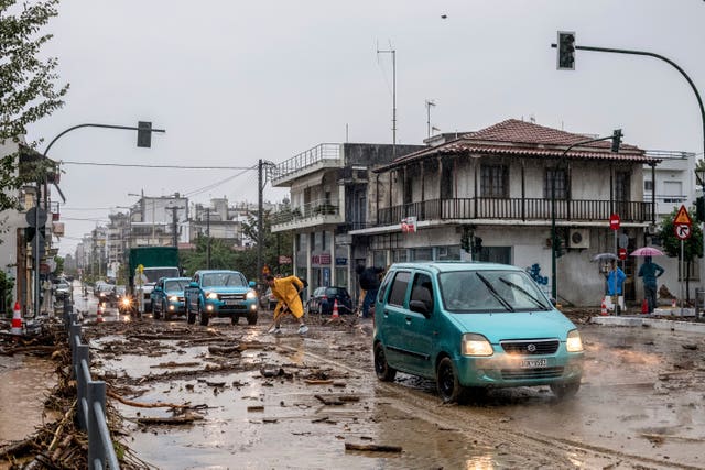 951f37e462e2418fb610070717cdab3f-1 A man cleans debris from floodwater in the town of Volos, central Greece