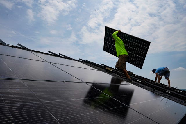 5c5c8a9c1bf6427380a0d9b512949112 A person carries a panel at a solar farm in the US
