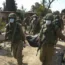 Israeli soldiers carry the body of a person killed in the Hamas attack in Kfar Azza