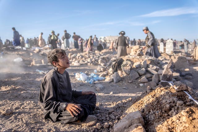 cb93371fddd54be384522a7875a34320 An Afghan boy mourns next to the grave of his brother