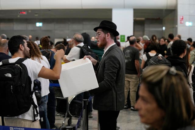 db1b20f516eb40faad998b8ce8fa877a A man distributes sandwiches to passengers who are waiting in a queue to board flights to Israel at the Eleftherios Venizelos International Airport in Athens, Greece