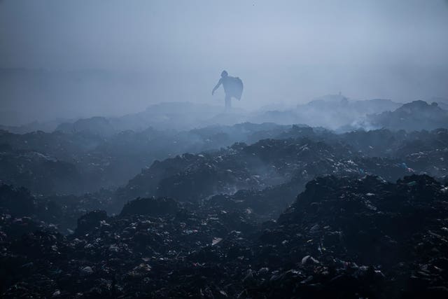 1dca54779cc3443aa9474ff7ec7a3404 A Palestinian man collects plastic as smoke rises from a fire in a landfill, east of Gaza City