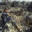 A man sits on the rubble as others wander among debris of buildings targeted by Israeli airstrikes in Jabaliya refugee camp, northern Gaza Strip, on Wednesday