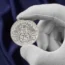 Charles's 75th birthday silver crown coin in a gloved hand