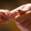 A baby holding its mother's finger
