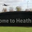 A plane flies over a 'Welcome to Heathrow' sign