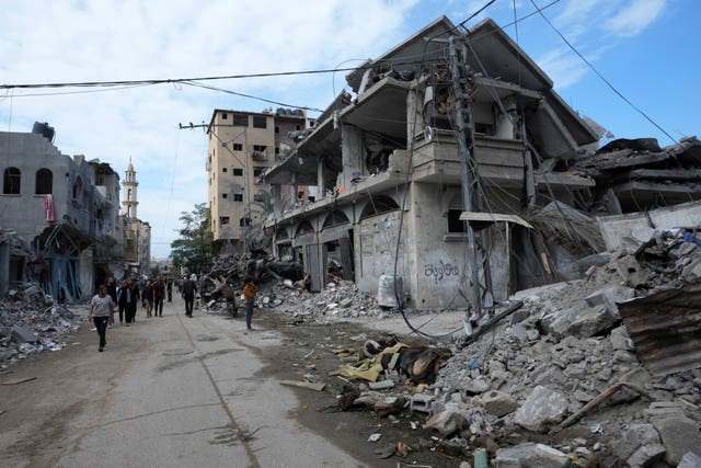 dc9098ebd87740bda2ebd15a5063d711 Palestinians walk past buildings destroyed in the Israeli bombardment of the Gaza Strip, at the main road in Bureij refugee camp, Gaza Strip