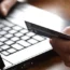 A person holding a bank card next to a laptop