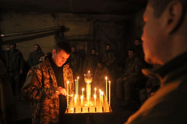 e6a6a8143dfe4924bfce013b32a6ea75-1 A Ukrainian serviceman of the 72nd mechanised brigade lights a candle during the sacred liturgy before the upcoming Christmas at the frontline near Vuhledar, Ukraine