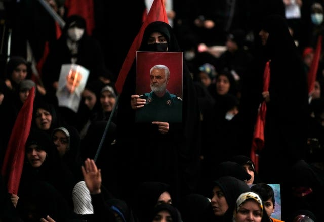 7aeaae12ef62435397a6200886b4de90 A woman holds up a poster of Qassem Soleimani during a commemoration in Tehran