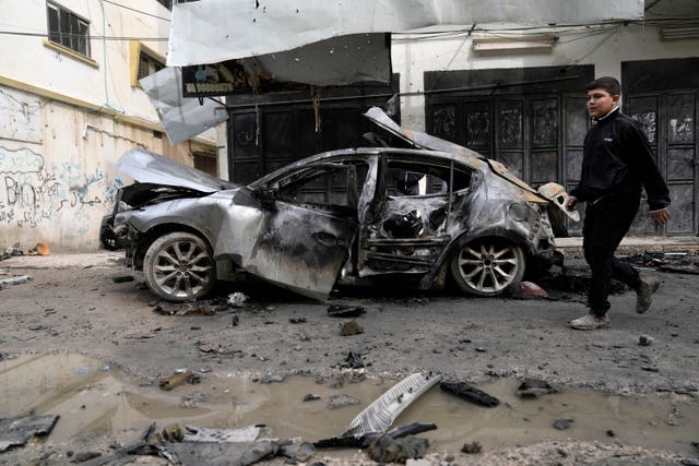 f2389c0a20e14d4b8b9d92be8e695d83 A Palestinian boy walks past a car destroyed in an Israeli drone strike in the West Bank Jenin refugee camp