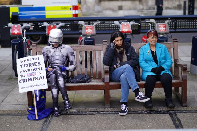 2-75545172 A protester dressed as RoboCop sits on a bench near the Palace of Westminster, as the Chancellor delivers his Budget to Parliament