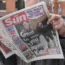A man reads a copy of The Sun newspaper in central London